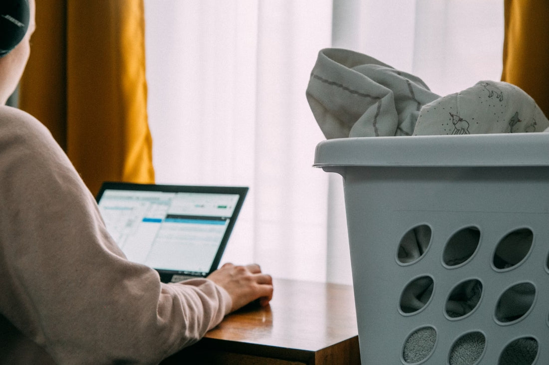 A man is working at home and on his right side is stacking some clothes washing by malory eczema friendly laundry detergent