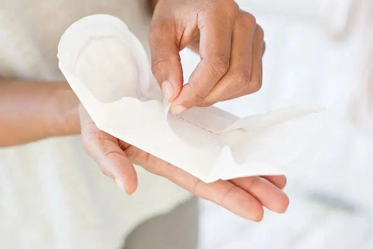 A woman is unfolding a piece of Malory sanitary pads